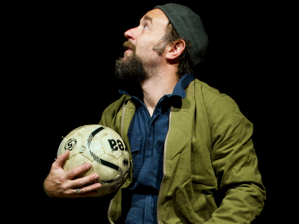 Un uomo di profilo, cappellino in testa, pallone da calcio in mano