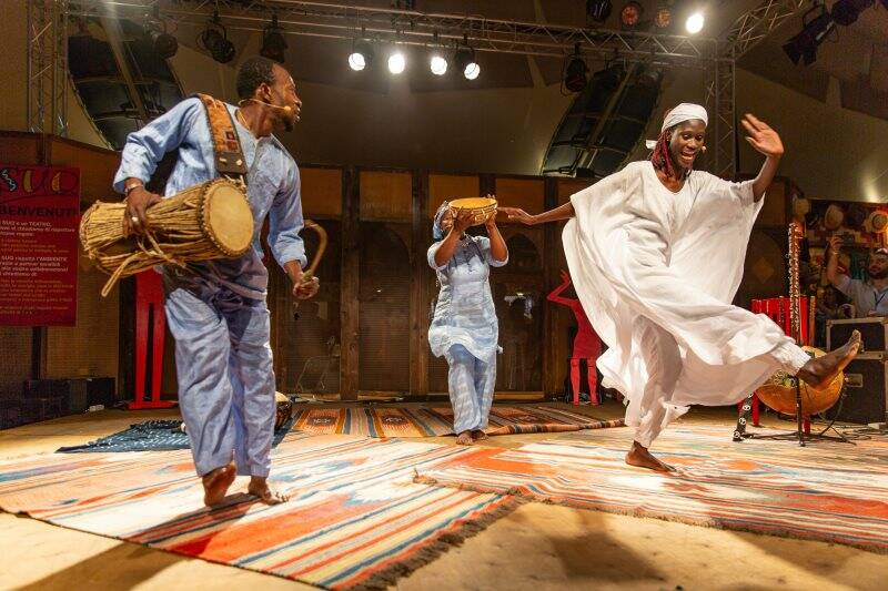 Due musicisti africani con tamburi e una donna africana che danza