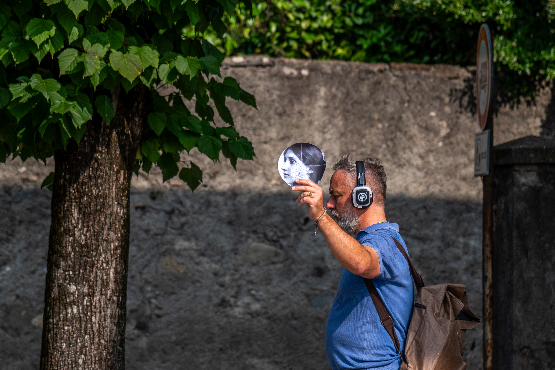 un uomo indossa cuffie audio e in mano ha una foto in bianco e nero con un volto di donna