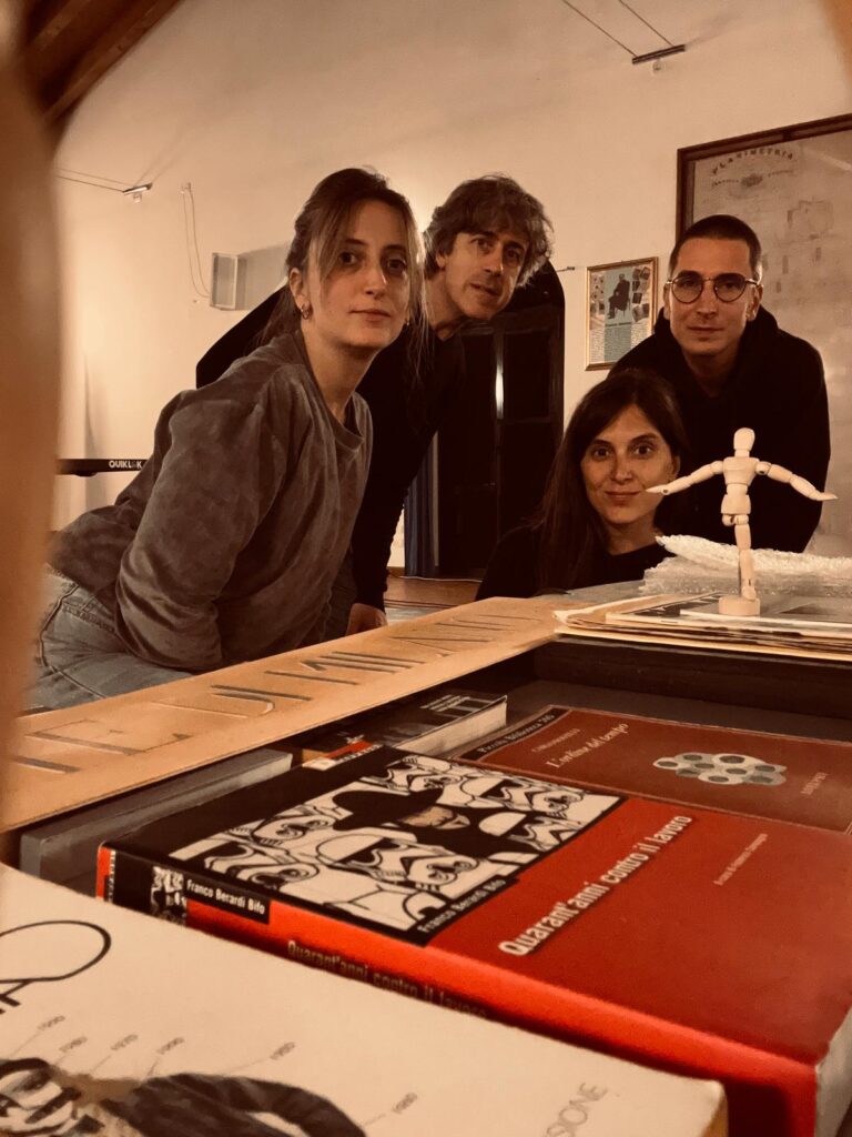 due donne e due uomini in posa vicino a un tavolo con libri e una marionetta con gamba spezzata