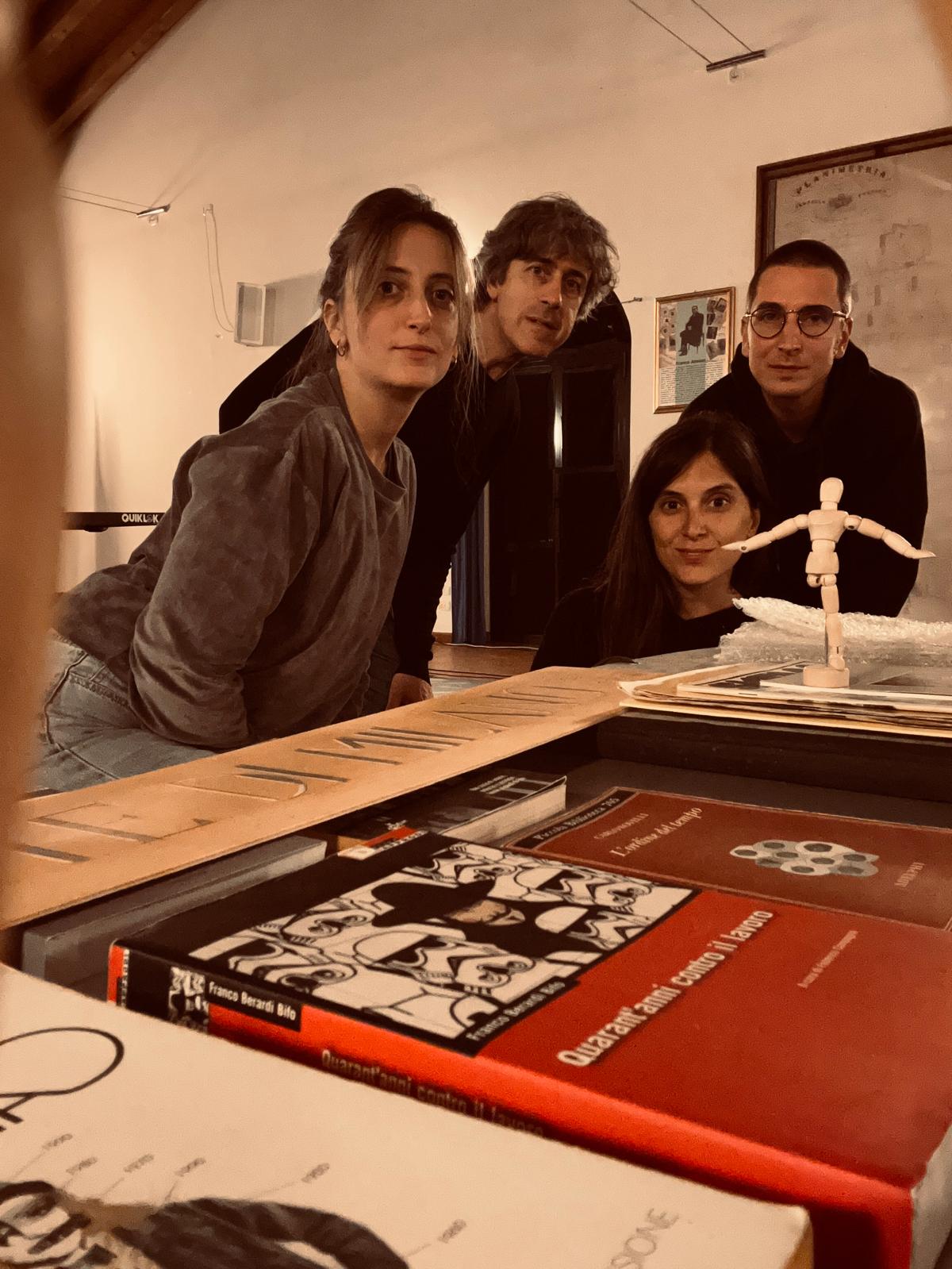 due donne e due uomini in posa vicino a un tavolo con libri e una marionetta con gamba spezzata